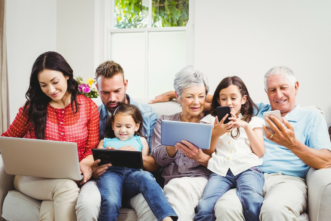 happy family using technologies while sitting on sofa