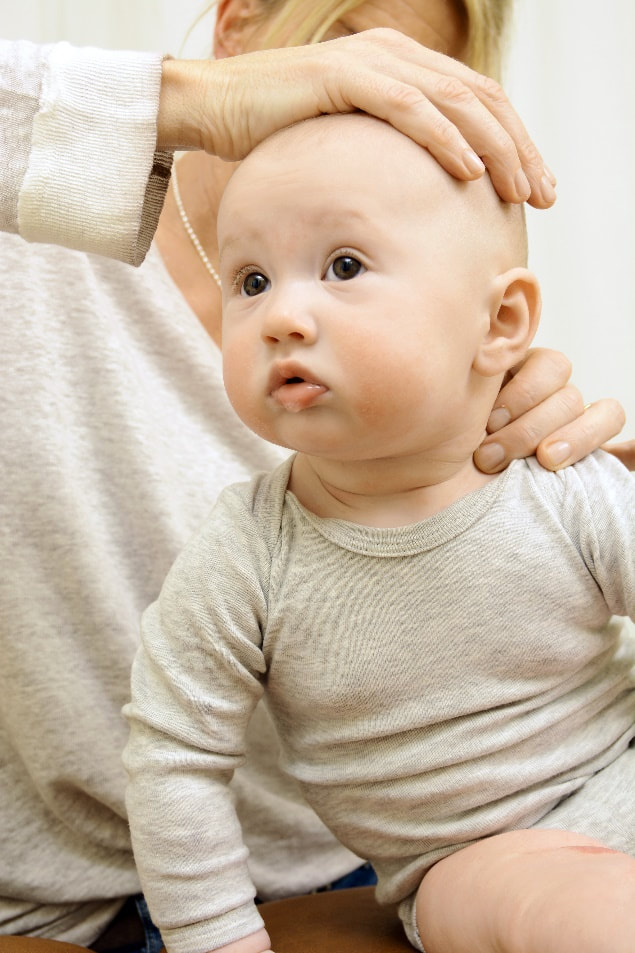 alternative practitioner treats a baby's head