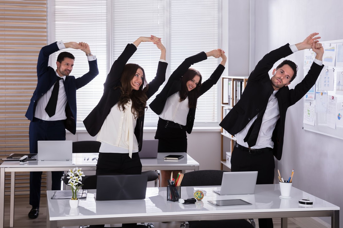 Happy Businesspeople Doing Stretching Exercise Behind Desk